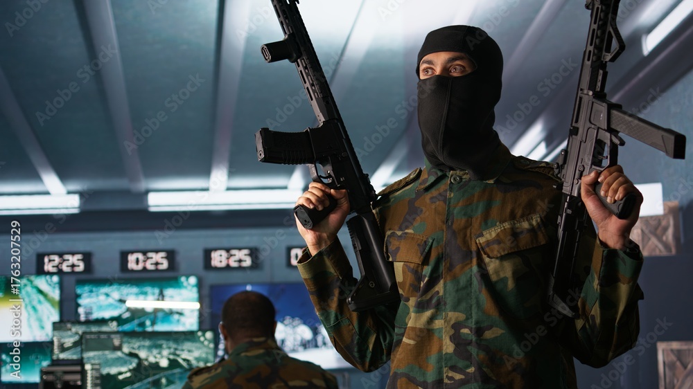 Obraz premium Terrorist wearing mask holding rifles, prepared to start guerilla warfare operation against enemies. Rebel forces insurgent with weapon in hidden base starting offensive against opponents, camera B