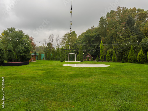 Fototapeta Naklejka Na Ścianę i Meble -  Outdoor wedding or event space with string lights and a circular stage on a green lawn
