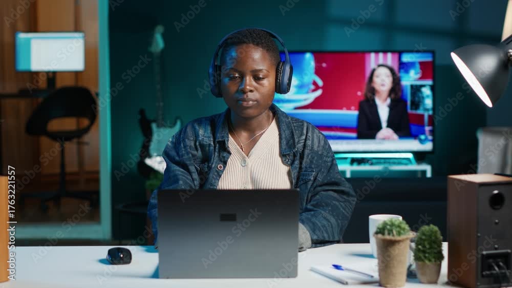 Woman listening music in living room office while answering emails from ...