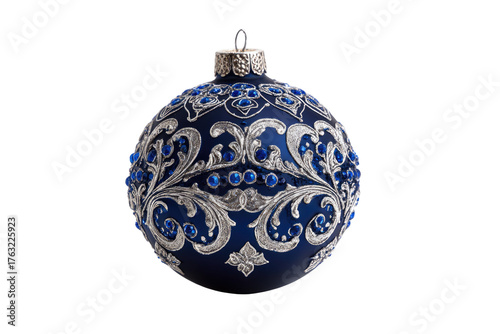A dark blue Christmas ornament with silver filigree and blue jewels against a black background