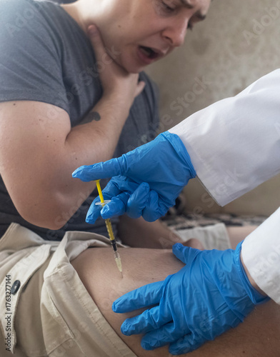 A man injects himself with adrenaline into his thigh during anaphylactic shock. First aid for allergies, emergency medical care for an allergic reaction.