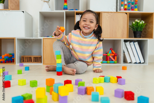 toddler girl playing block toy to stacks building cubes at home