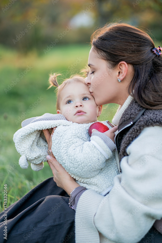 Obraz premium Young woman with child playing on a walk. Mother and little daughter picking ripe apples in autumn park. Healthy motherhood.