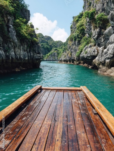 Boat ride through Ha Long Bay Vietnam point of view from wooden deck on emerald water surrounded by limestone cliffs