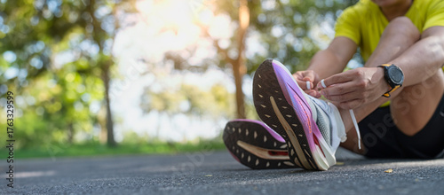 Runner lacing up shoes before morning exercise outdoors