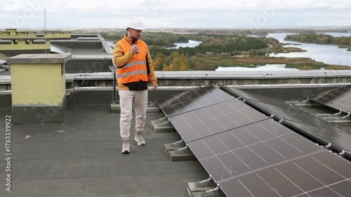 Engineer with walkie-talkie inspecting solar panels, concept of renewable energy and sustainable technology.