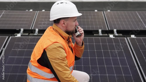 Engineer with walkie-talkie inspecting solar panels, concept of renewable energy and sustainable technology.