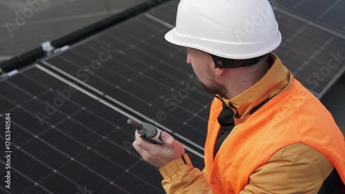 Engineer with walkie-talkie inspecting solar panels, concept of renewable energy and sustainable technology.