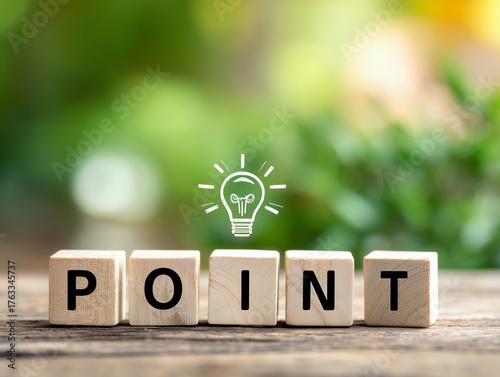 木製ブロックで並べたPOINTの文字と電球アイコンがひらめきを表現するビジネスイメージ