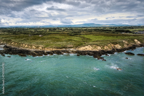Foto Aerial view of rugged Irish coastline with rocky cliffs, green headland, and tur