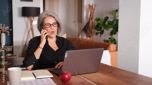 Businesswoman managing her business from home, using laptop and smartphone
