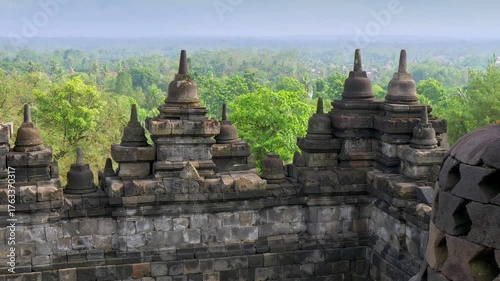 Explore ancient stone structures at Borobudur Temple surrounded by lush green jungle in Central Java, Indonesia during clear sunny weather. Gimbal shot