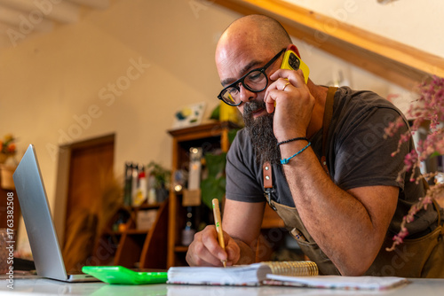 Bild auf Leinwand Florist owner talking on phone managing small business