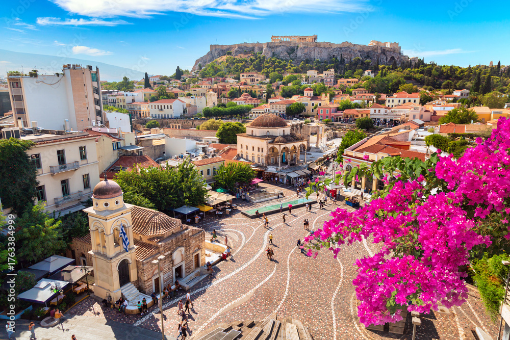 Obraz premium Skyline of Athens with Monastiraki square, Church of Pantanassa and Acropolis hill during summer sunny day. Athens, Greece. Pink bougainvillea flower in the foreground.