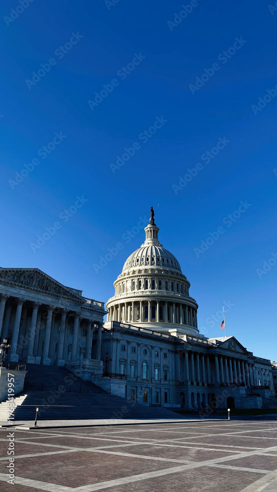 Naklejka premium Capitol building in Washington DC with dome and steps under clear blue sky in USA