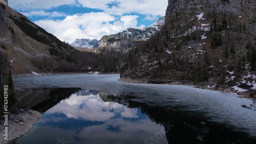 Experience stunning aerial views of Lahngangsee, featuring winter landscapes, snow-covered banks, and reflections in the tranquil water under a blue sky.