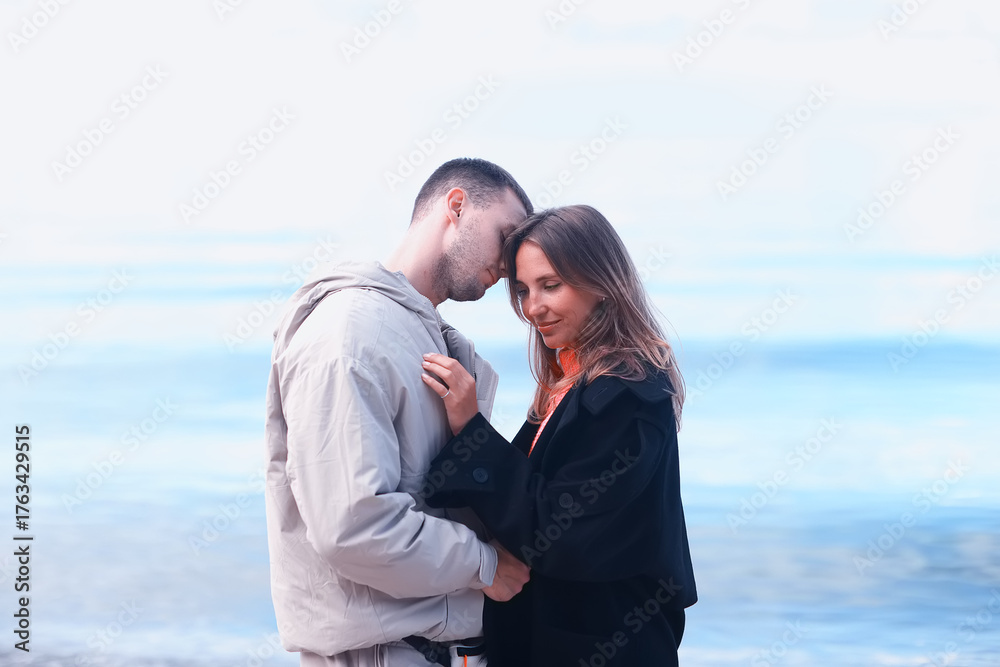 Obraz premium man and woman, couple in love on the seashore spring or autumn view seasonal photo in warm clothes