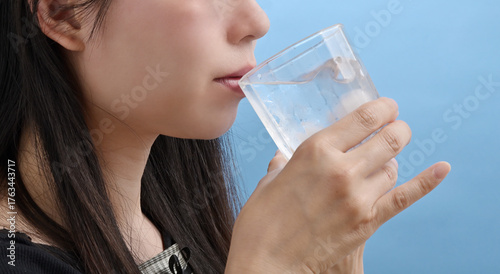 グラスの水を飲む若い日本人女性	