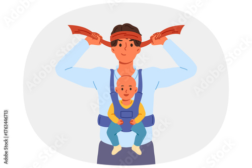 Man super father with baby in arms, tying bandage on head and preparing to raise son on own. Businessman father wants to work and raise child at same time, due to absence of mother and nanny for baby