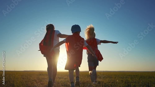 A group of kids are running around with superheroes. Hero super child concept. Group of lifestyle children running together, silhouette of. superheroes. A group of kids run together like superheroes.