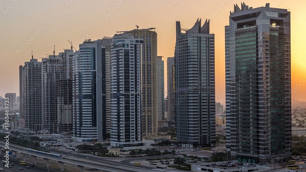 Fototapeta premium Aerial view of Jumeirah lakes towers skyscrapers night to day timelapse with traffic on sheikh zayed road.