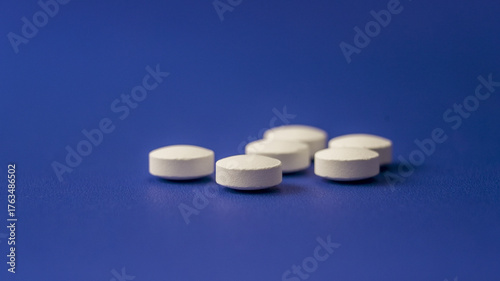 White round tablets scattered on a blue background highlighting the medication's simplicity and accessibility