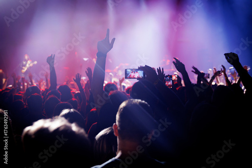 Fans raise hands at rock concert with stage lights