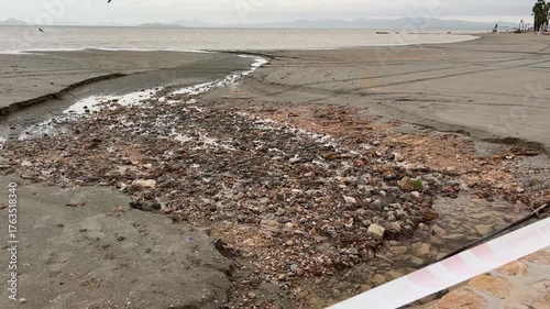 Murcia, Spain - October 12, 2025: Orange Civil Protection tape blocks access to a quiet beach under cloudy skies