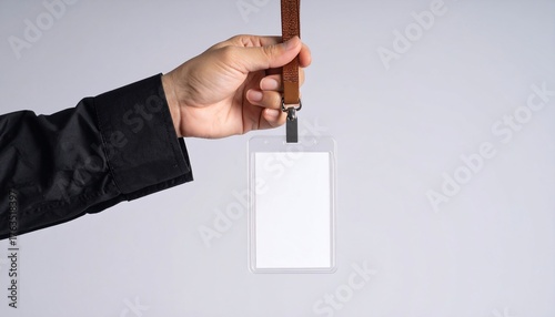 A hand holding an empty id card with a lanyard against a white background.