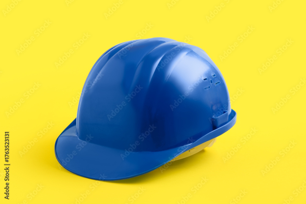 Fototapeta premium Blue hardhat on yellow background