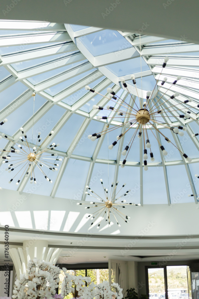 Obraz premium A spacious room showcases a beautiful glass ceiling, allowing natural light to flood in. Modern light fixtures add a touch of elegance to the atmosphere and decor