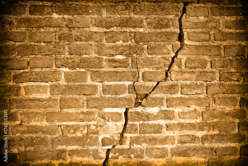 Dangerous old brick wall with deep crack due to structural failure, subsidence or damage from earthquake - vintage concept
