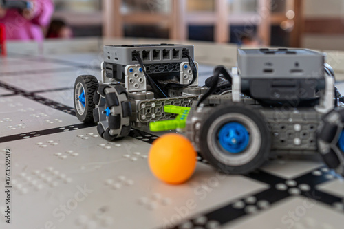 Robots interact with a ball on a grid surface during a technology demonstration