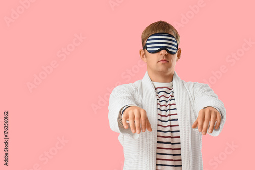 Obraz na płótnie Male sleepwalker in pajamas on pink background