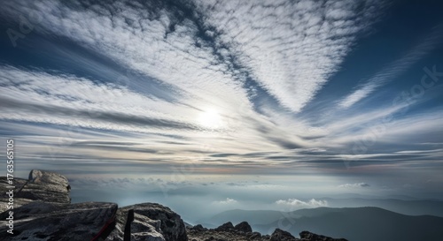 Breathtaking panoramic mountain vista from a high peak with dramatic clouds and hazy valleys stretching to the horizon.