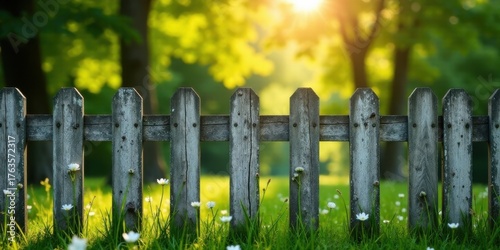 Fototapeta Naklejka Na Ścianę i Meble -  Rustic wooden fence amidst a vibrant summer meadow bathed in golden sunlight, wildflowers blooming at the base, creating a tranquil pastoral scene.