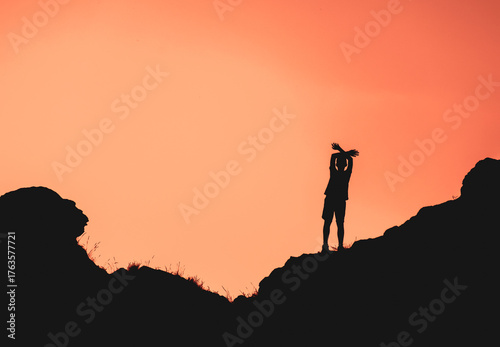A person is standing on a hill with a beautiful sunset in the background