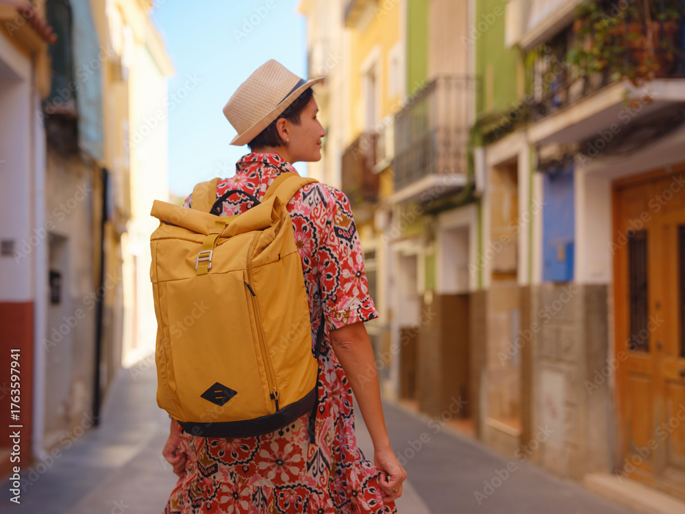 Fototapeta premium Woman strolls through colorful streets of Spanish coastal town