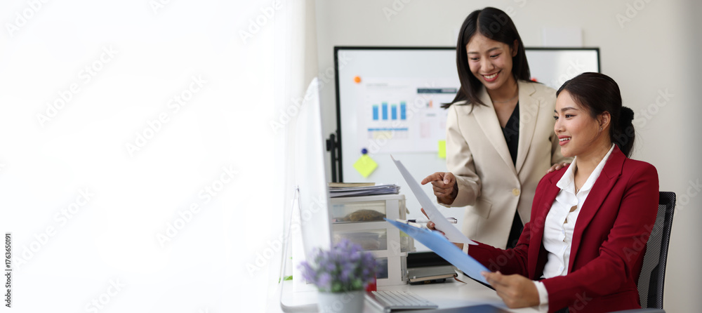 Fototapeta premium Businesswoman working together analyzing financial charts on computer and documents in office.