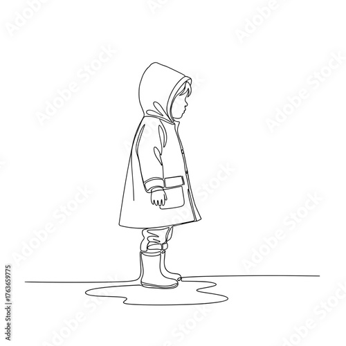 Child standing in raincoat next to puddle in autumn weather  