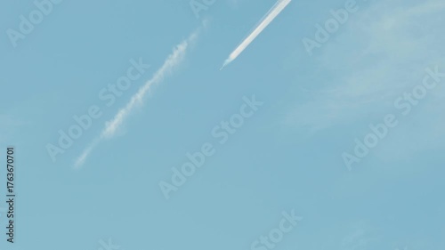 青空と白い飛行機雲。長く尾を引き風に流されていく
