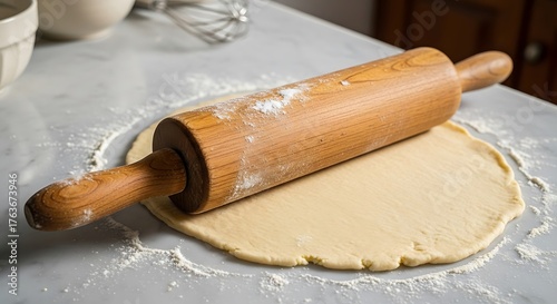 Wooden rolling pin resting on freshly rolled out dough.