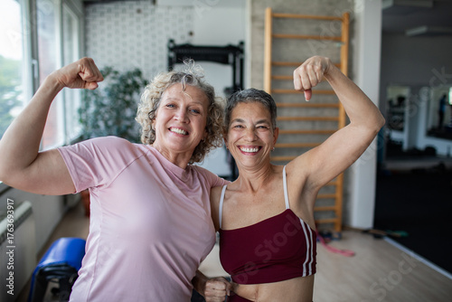 Two mature women flexing in a gym