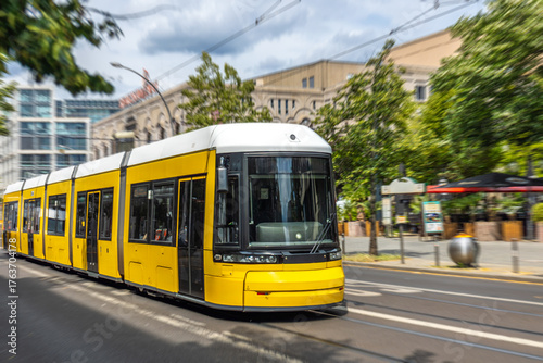 Yellow city tram on urban street. Modern public transport.