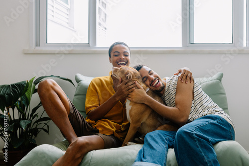 Photography Smiling couple cuddling caramel rescue dog on sofa at home