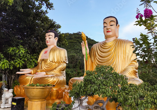 Two serene sitting Buddha statues at Chua Da Bao Pagoda in Nha Trang, Vietnam. Peaceful spiritual scene in a traditional temple surrounded by nature and mountain views.