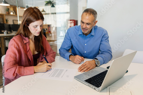 Tableau sur toile Young woman signing a job contract with human resources manager during an interview meeting at the office