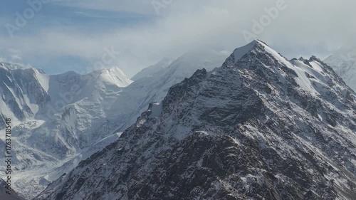 Majestic snow-capped mountains are showcased in a sweeping panoramic view, revealing intricate textures and dramatic peaks, as the camera smoothly pans across the breathtaking landscape