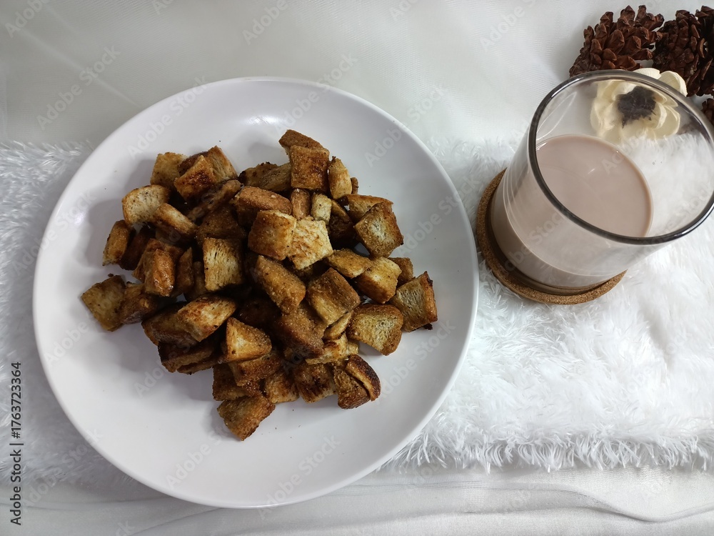 Fototapeta premium view of bread caramel popcorn on a white plate with a glass of milk on a white tablecloth