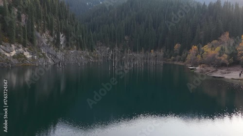 Serene lake view showcasing autumn foliage and reflections on water, as the camera pans to reveal the surrounding landscape, highlighting the tranquil atmosphere and natural beauty